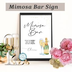 there is a framed sign with champagne glasses and flowers on the table next to it