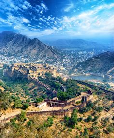 an aerial view of a city with mountains in the background and blue skies above it