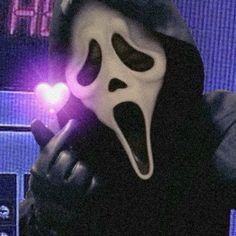 a person wearing a ghost mask holding a cell phone