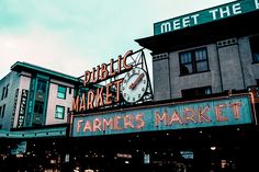 a sign that says farmers market and public market on the side of a building with a clock