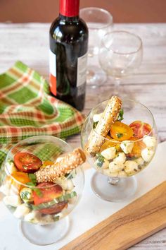 two wine glasses filled with food on top of a table