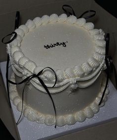 there is a white cake with black ribbons on it