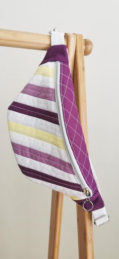 a purple and yellow striped purse hanging on a wooden chair