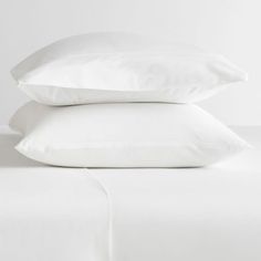 two white pillows sitting next to each other on a bed