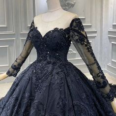 a mannequin wearing a black dress with sheer sleeves and an intricate lace pattern