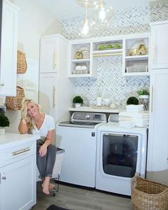 a woman sitting on the kitchen counter next to a washer and dryer in front of her