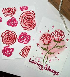 two cards with roses on them sitting next to each other