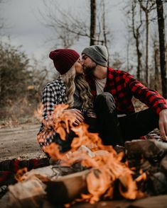 a man and woman sitting next to a campfire