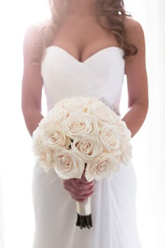 a bride holding a bouquet of white roses