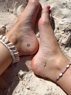 a woman's foot with a star and moon tattoo on it sitting in the sand