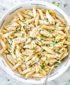 a white bowl filled with pasta and parsley on top of a marble countertop