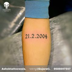 a person with a tattoo on their arm that reads 21 2 2009, which is written in black ink