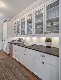 a kitchen with white cabinets and black counter tops on top of a brown area rug