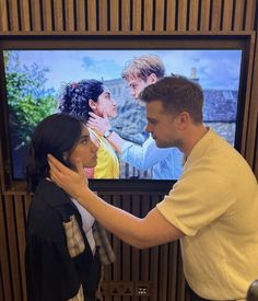 a man standing next to a woman in front of a tv