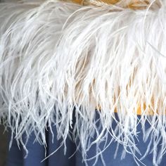 a close up view of the back of a chair with white and yellow feathers on it