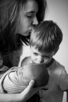 a mother kissing her son's face while he holds his baby