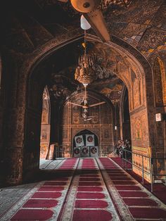 the inside of an ornate building with red carpet and chandelier hanging from the ceiling