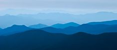 the mountains are covered in blue hues as seen from an airplane flying over them