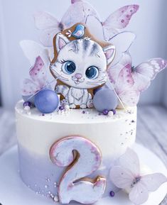 a white cake topped with a cat and butterflies