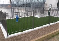 a blue fire hydrant sitting in the middle of a fenced off area next to a parking lot