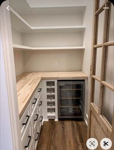 an empty walk in pantry with shelves and drawers on each side, open to reveal the wine cellar