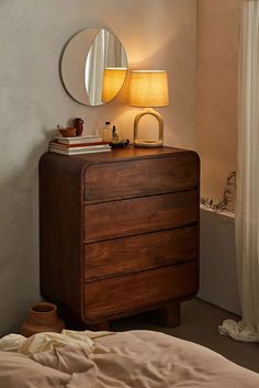 a wooden dresser sitting next to a bed under a mirror on top of a wall