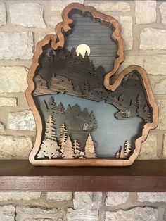 a wooden clock with a lake and mountains in the middle on a shelf next to a brick wall