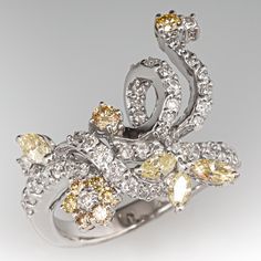 This lovely ring features a floral and ribbon design and is prong set with a total of fifty-one (51) round brilliant cut diamonds and four (4) marquise brilliant cut diamonds. The ring measures 21.1mm at the top, rises 6.4mm above the finger, tapering to 2.9mm wide and 1.2mm thick at the base of the shank. This ring is currently a size 6.5. Luxury Marquise Multi-stone Diamond Ring, Luxury Marquise Cut Multi-stone Diamond Ring, Luxury Multi-stone Marquise Cut Diamond Ring, Marquise Multi-stone Diamond Ring, White Gold Marquise Multi-stone Diamond Ring, Cubic Zirconia Marquise-cut Multi-stone Diamond Ring, Marquise Cut Multi-stone Cubic Zirconia Diamond Ring, Marquise Cut Multi-stone Diamond Ring For Anniversary, Multi-stone Cubic Zirconia Marquise Cut Ring