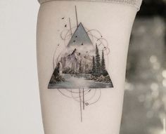 a woman's arm with a mountain and forest tattoo on the left side of her leg