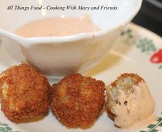 three crab cakes on a plate next to a bowl of dip and dipping sauce in it