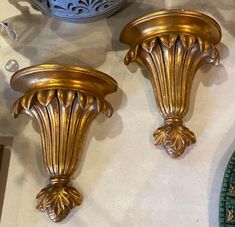 two gold colored vases sitting next to each other on a table