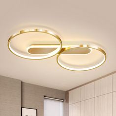 two circular lights that are on the ceiling above a bed in a room with beige walls