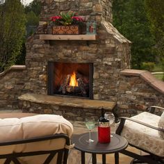 an outdoor fireplace with two chairs around it