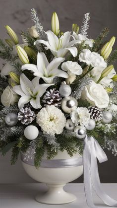 a white vase filled with lots of flowers and pineconis on top of a table