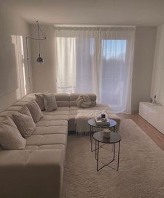 a living room filled with furniture and a large window next to a white curtained wall