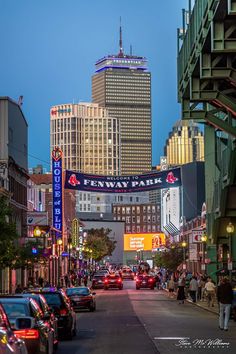 cars are parked on the street in front of tall buildings and skyscrapers at dusk