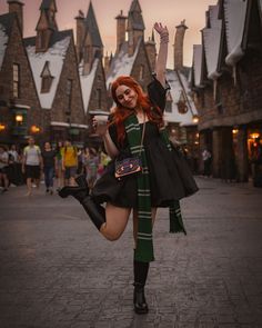 a woman with red hair and black boots is posing in front of hog potter's house