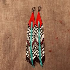 two red, white and blue beaded earrings on a brown cloth with black hooks