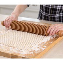 a person rolling dough on top of a wooden board