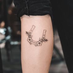 a tattoo on the leg of a woman with flowers and a letter u in it