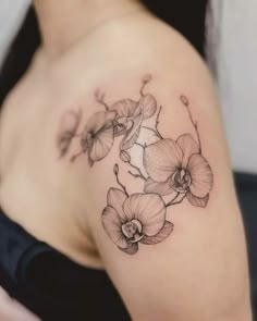 a woman's shoulder tattoo with flowers on the left side of her arm and chest