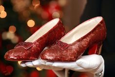 a pair of red shoes sitting on top of a white glove