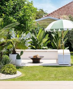 a white bench sitting in the middle of a lush green yard with an umbrella over it