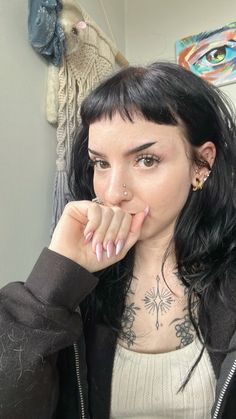 a woman with long black hair and piercings on her neck is looking at the camera