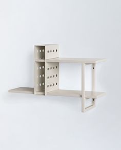 a white shelf with holes on the bottom and two shelves below it that are attached to each other