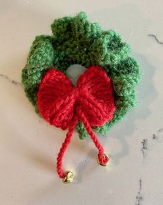 a crocheted wreath with a red bow and bells hanging from it's side