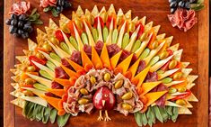 an elaborately designed fruit and vegetable dish on a wooden board with utensils