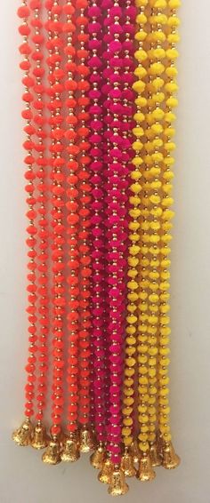 many different colored beads are lined up on a white surface with gold bells in the middle