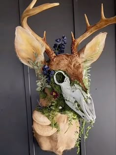 a deer head with antlers and flowers on it's face is hanging from the wall