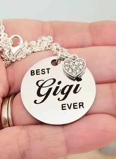 Best Gigi Ever Silver Pendant Necklace Show your Gigi just how much she means to you with this heartfelt necklace  ♡ Laser engraved with "Best Gigi Ever" and accented with a crystal heart charm ♡ Polished stainless steel pendant measures 1 inch ♡ 18-inch silver cable chain measures 18-inches long ♡ Lobster clasp closure ♡ Hypoallergenic/Nickel fee Ships within 24 hours of purchase Monday-Saturday Gift Packaging & Messages: Your item will be lovingly packaged and labeled as a handmade item.  Item Meaningful Jewelry For Birthday Gifts, Meaningful Hand Stamped Jewelry For Birthday Gift, Charm Jewelry For Mother's Day Birthday Gift, Mother's Day Birthday Gift Charms Jewelry, Meaningful Silver Jewelry For Birthday Gift, Father's Day Gift Jewelry With Charms, Father's Day Gift Charms Jewelry, Father's Day Jewelry Charms For Gifts, Silver Charm Necklaces For Birthday And Mother's Day